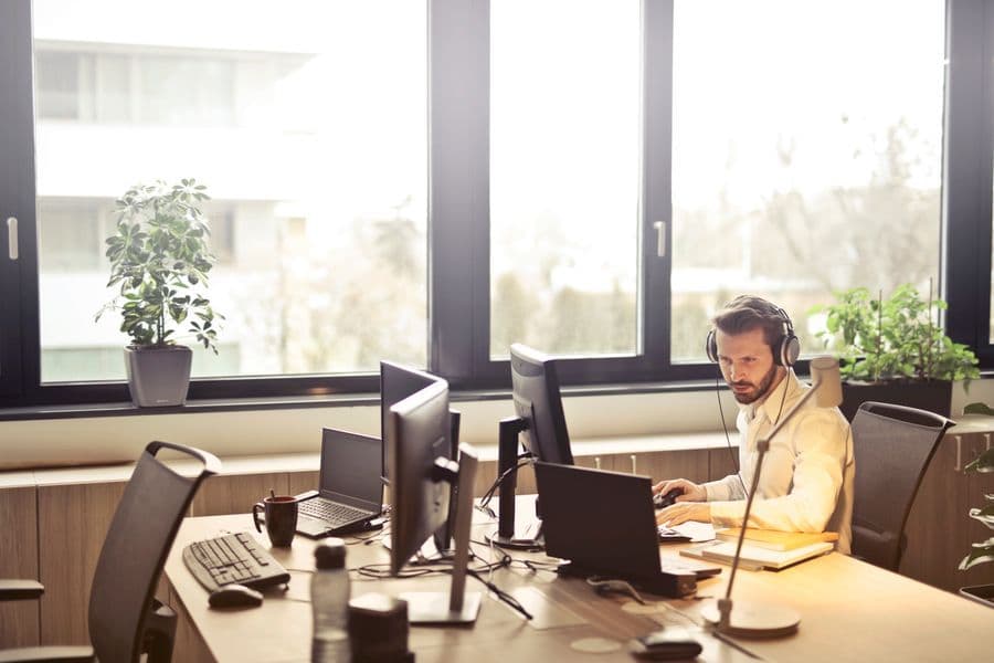 Helpdeskmedewerker met headset achter een bureau met planten